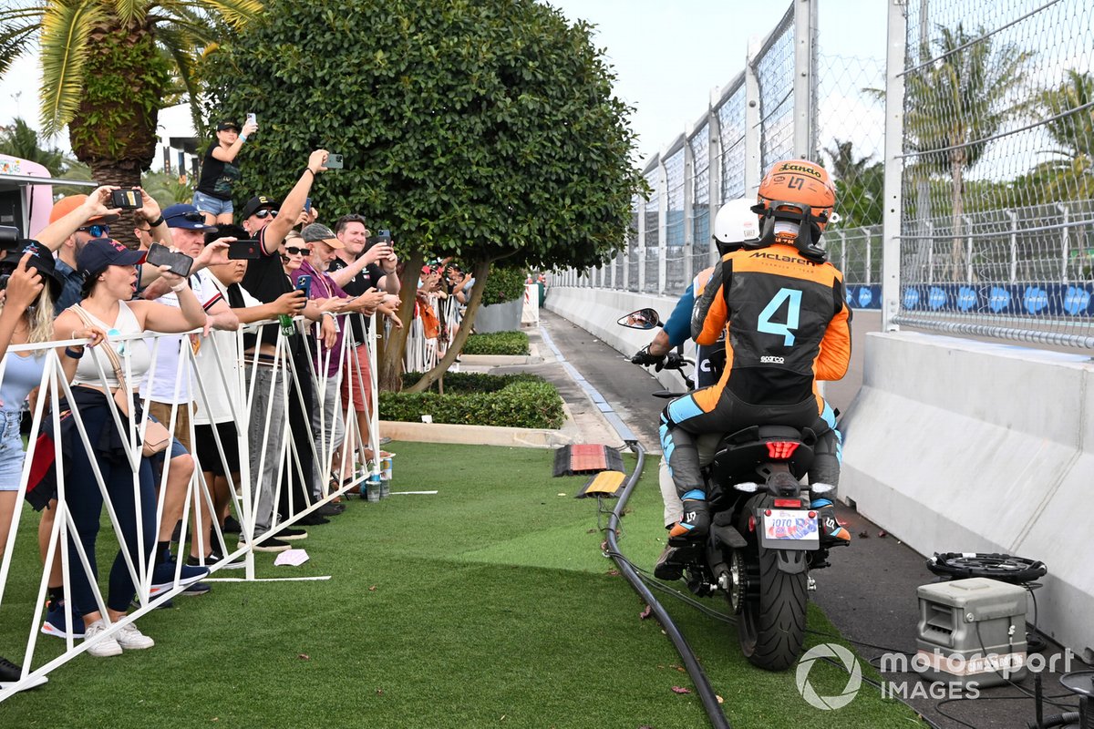 Lando Norris, McLaren, is given a scooter ride back to the pits after crashing out of the race
