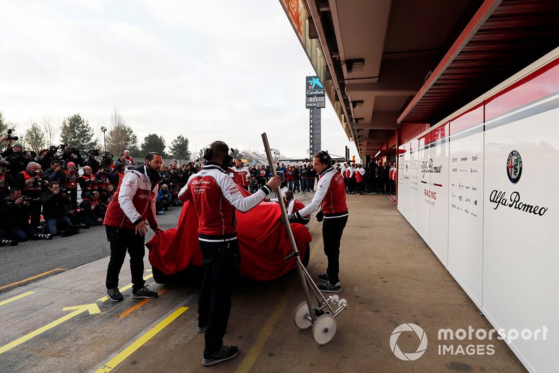 Alfa Romeo Racing mechanics with the new Alfa Romeo Racing C38 under covers