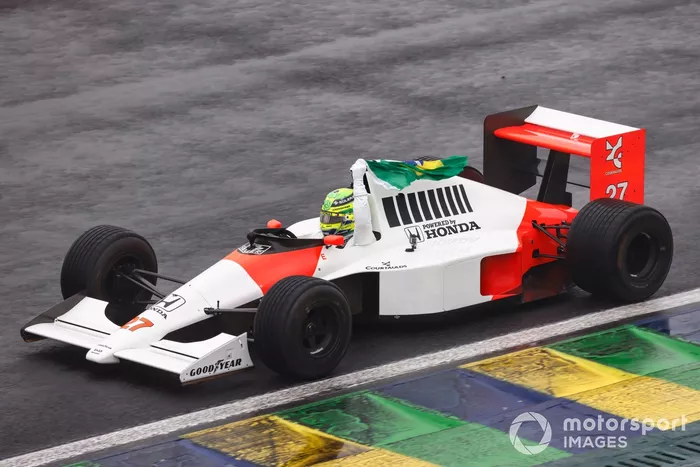 Lewis Hamilton conduce el McLaren MP4/5B de Ayrton Senna mientras sigue la bandera brasileña desde el cockpit