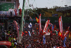 Confetti and streamers fall around the huge crowd of Ferrari fans gathered for the podium ceremony
