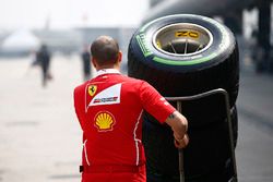 A Ferrari team members pushes a stack of Pirelli tyres