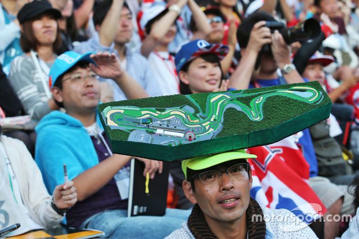 Fans en la tribuna con el mapa del circuito en la cabeza