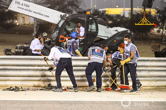 Los oficiales retiran los restos del monoplaza de Romain Grosjean, Haas VF-20, después del accidente en la primera vuelta