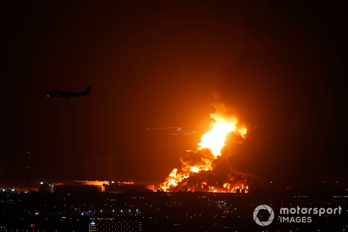 An airliner is silhouetted by a fire in Jeddah beyond the circuit