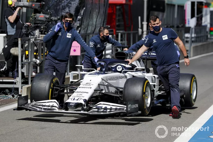 Los mecánicos de AlphaTauri empujan el AlphaTauri AT01 por el pit lane