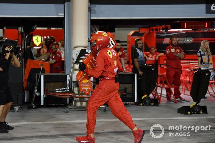 Un miembro del equipo de boxes de Ferrari con el morro dañado del coche de Sebastian Vettel, Ferrari SF90