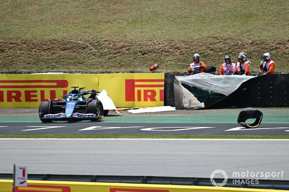Sergio Perez, Red Bull Racing RB19, passes the damaged car of Esteban Ocon, Alpine A523