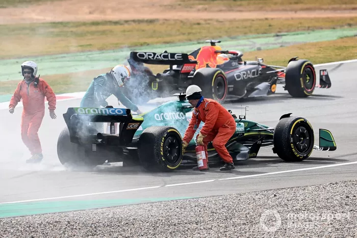 Oficiales de pista asisten a Sebastian Vettel, Aston Martin AMR22, después de que un fallo técnico produzca humo