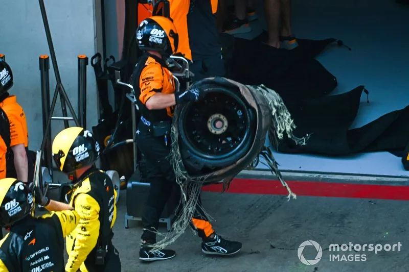 Le pneu endommagé est retiré de la voiture de Lando Norris, McLaren MCL38