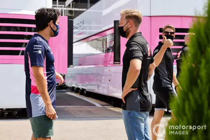 En su regreso al paddock tras una ausencia forzada por un virus, Sergio Pérez, de Racing Point, habla con Kevin Magnussen, de Haas F1, mientras Romain Grosjean, de Haas F1, da el visto bueno
