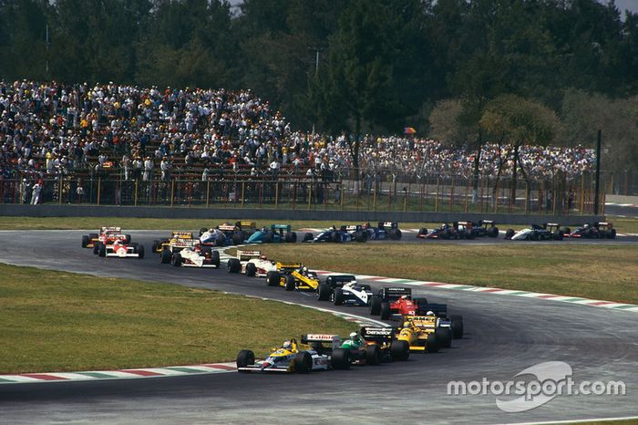 Nigel Mansell, Williams FW11B Honda, lidera a Teo Fabi, Benetton B187 Ford, Ayrton Senna, Lotus 99T Honda, y el resto del grupo en la primera vuelta