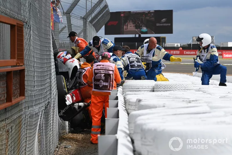 Los oficiales de pista y médicos asisten a Zhou Guanyu, Alfa Romeo C42