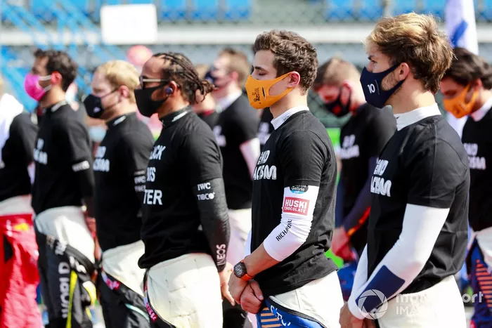 Los pilotos se ponen de pie para el himno nacional antes de la salida