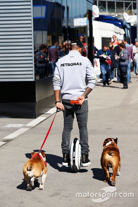 Lewis Hamilton, de Mercedes AMG F1 en un hoverboard en el paddock con sus perros Roscoe y Coco