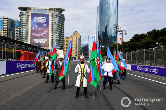 Artistas con trajes tradicionales con banderas de Azerbaiyán en la parrilla
