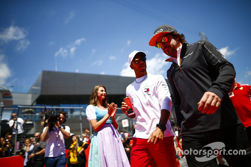 Grid Girls in national costume flank the drivers parade as Lewis Hamilton, Mercedes AMG F1, and Fernando Alonso, McLaren, pass
