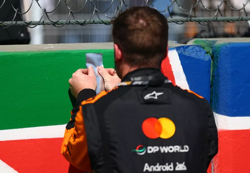 Une équipe McLaren place un autocollant sur la grille.