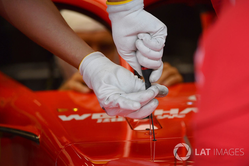 Dettaglio dei guanti sulle mani di un meccanico Ferrari