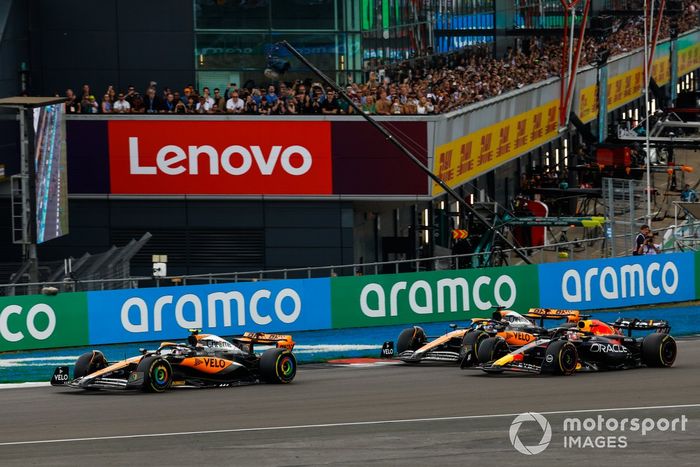 Lando Norris, McLaren MCL60, Max Verstappen, Red Bull Racing RB19, Oscar Piastri, McLaren MCL60, en la primera curva