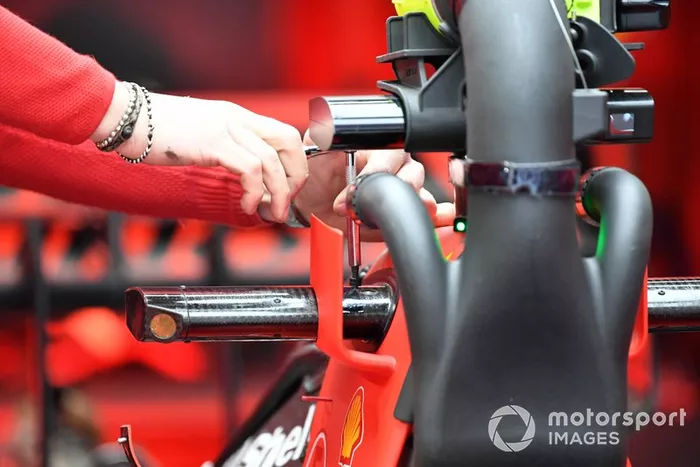 An engineer makes an adjustment to Sebastian Vettel's Ferrari SF1000 