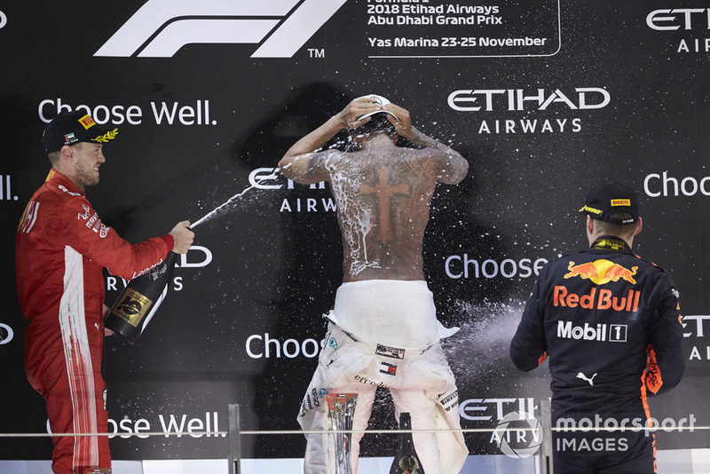 Lewis Hamilton, Mercedes AMG F1, 1st position, strips to the waist as Sebastian Vettel, Ferrari, 2nd position, and Max Verstappen, Red Bull Racing, 3rd position, spray him in celebration with Rose Water