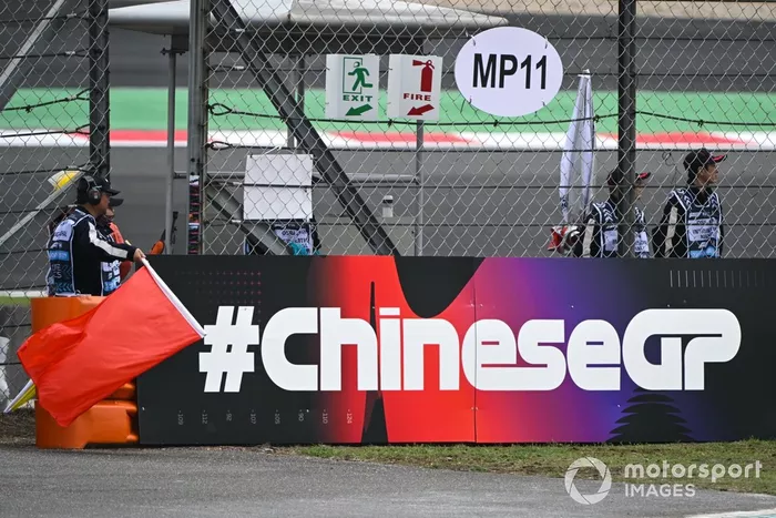 Les commissaires agitent le drapeau rouge après un petit incendie en bord de piste lors de la FP1