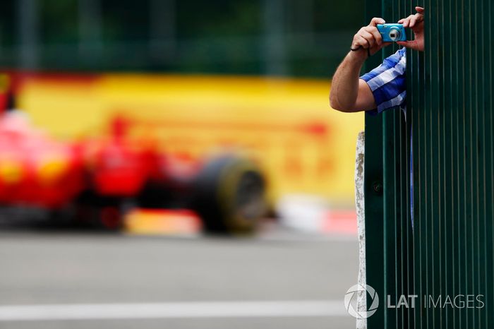 Un fan se inclina hacia fuera para tomar algunas fotos Kimi Raikkonen, Ferrari SF70H, pasa al fondo
