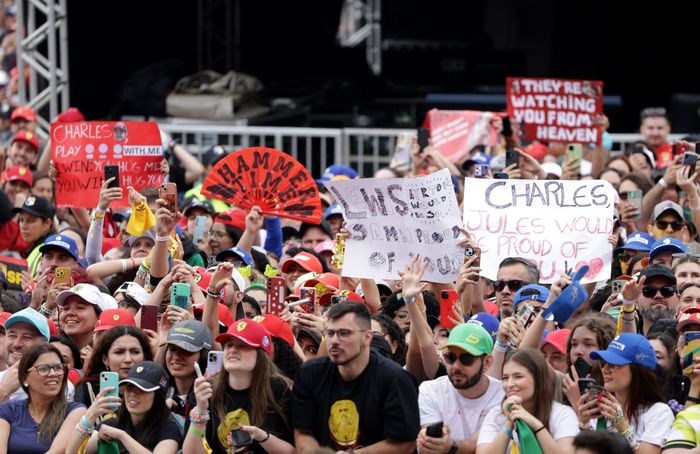 Fans hold up signs in support of Scuderia Ferrari in the fan zone.