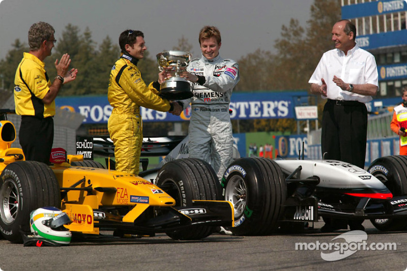 Giancarlo Fisichella receives the winner's trophy for the Brazilian GP from Kimi Raikkonen