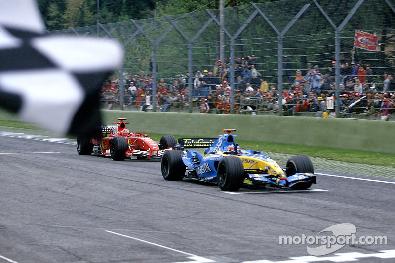 Fernando Alonso takes the checkered flag in front of Michael Schumacher