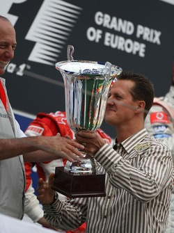 Michael Schumacher da la mano a Ron Dennis y el trofeo de constructores