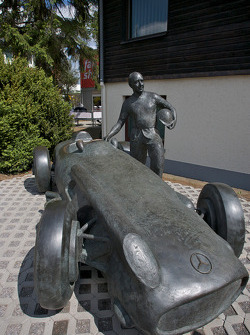 A bronze statue of Juan Manuel Fangio and his Mercedes-Benz W196 at the track entrance